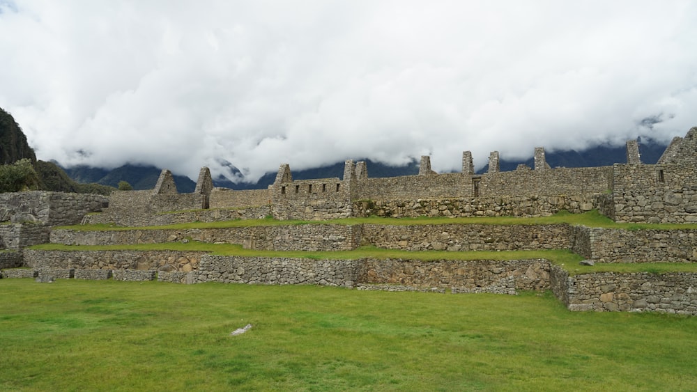 a grassy field with a stone structure in the middle of it