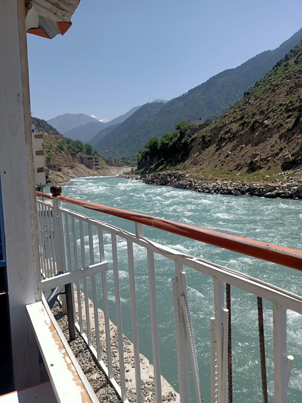 a balcony overlooking a river with mountains in the background