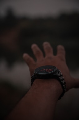 Close-up of a helping hand reaching out from a sleek watch, symbolizing connection and support.