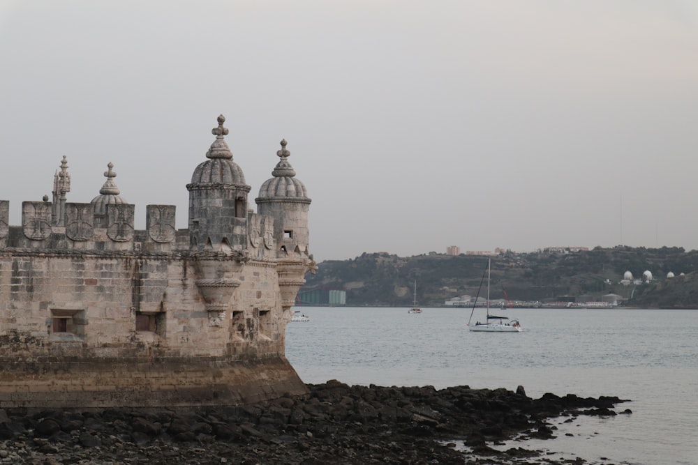 a castle sitting on top of a rocky shore next to a body of water