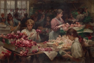 Several young women are engaged in arranging and packing roses within a dimly lit workshop. Roses, predominantly in shades of red and pink, cover the tables and are stacked in boxes. The setting suggests a sense of industrious activity, with each individual focused on handling the flowers.