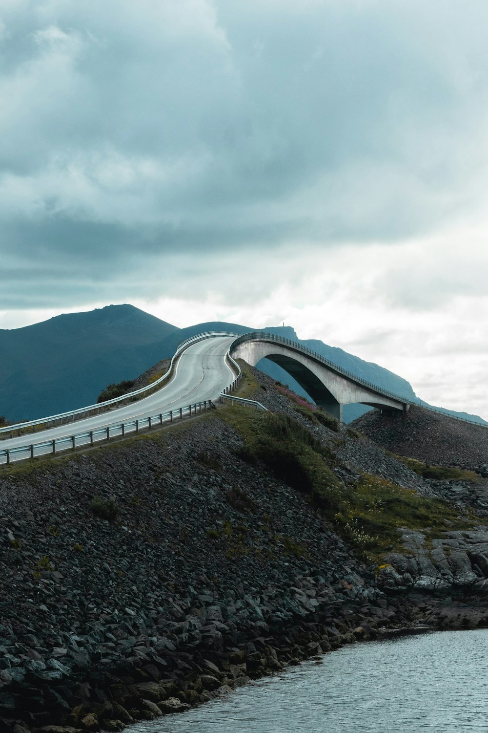 a curved road on top of a hill next to a body of water