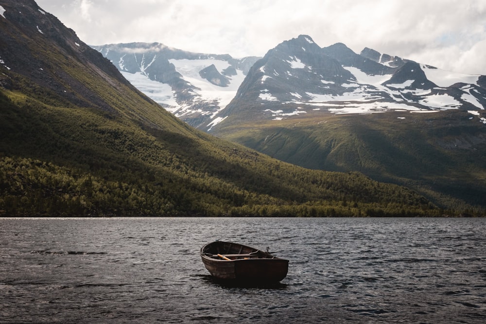 a boat floating on top of a lake surrounded by mountains