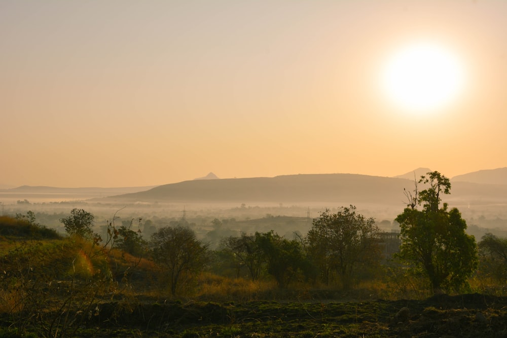 il sole sta tramontando sulle colline e sugli alberi