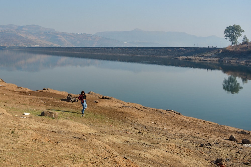 a man standing on top of a dry grass covered hillside