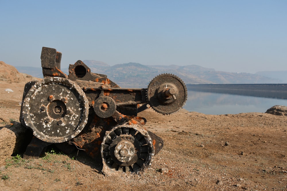 a rusted out machine sitting on top of a dirt field