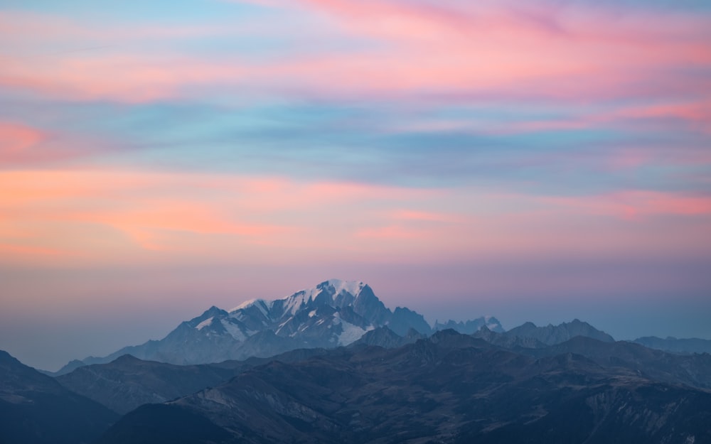 a mountain range with a pink and blue sky in the background