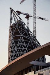 Modern building framework under construction with cranes.