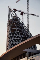Modern building framework under construction with cranes.