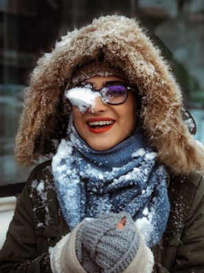 A smiling person bundled in a scarf and gloves, enjoying a crisp winter day outdoors.