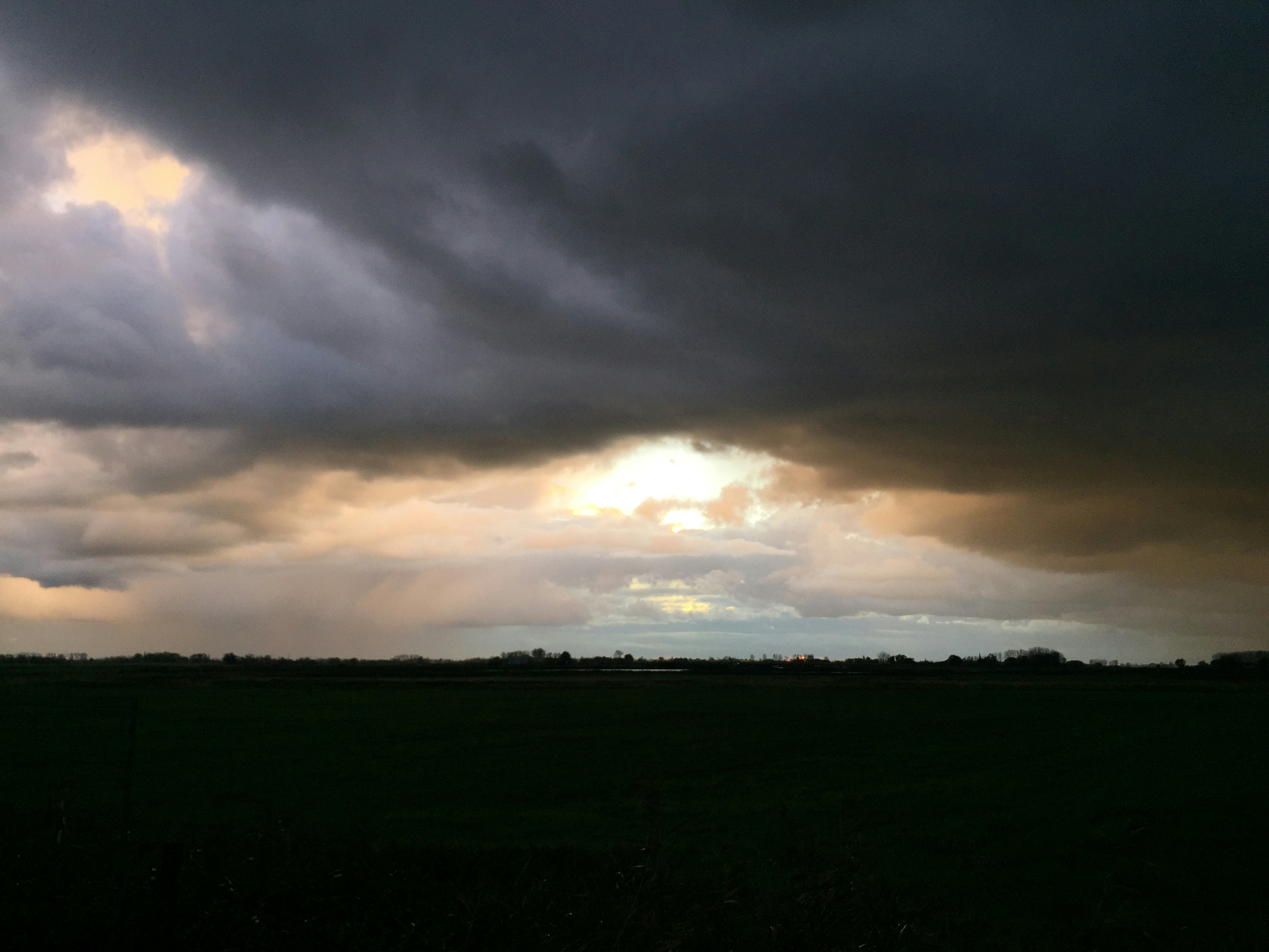 Split landscape showing stormy dark sky on one side and clear sunny sky on the other, dramatic contrast