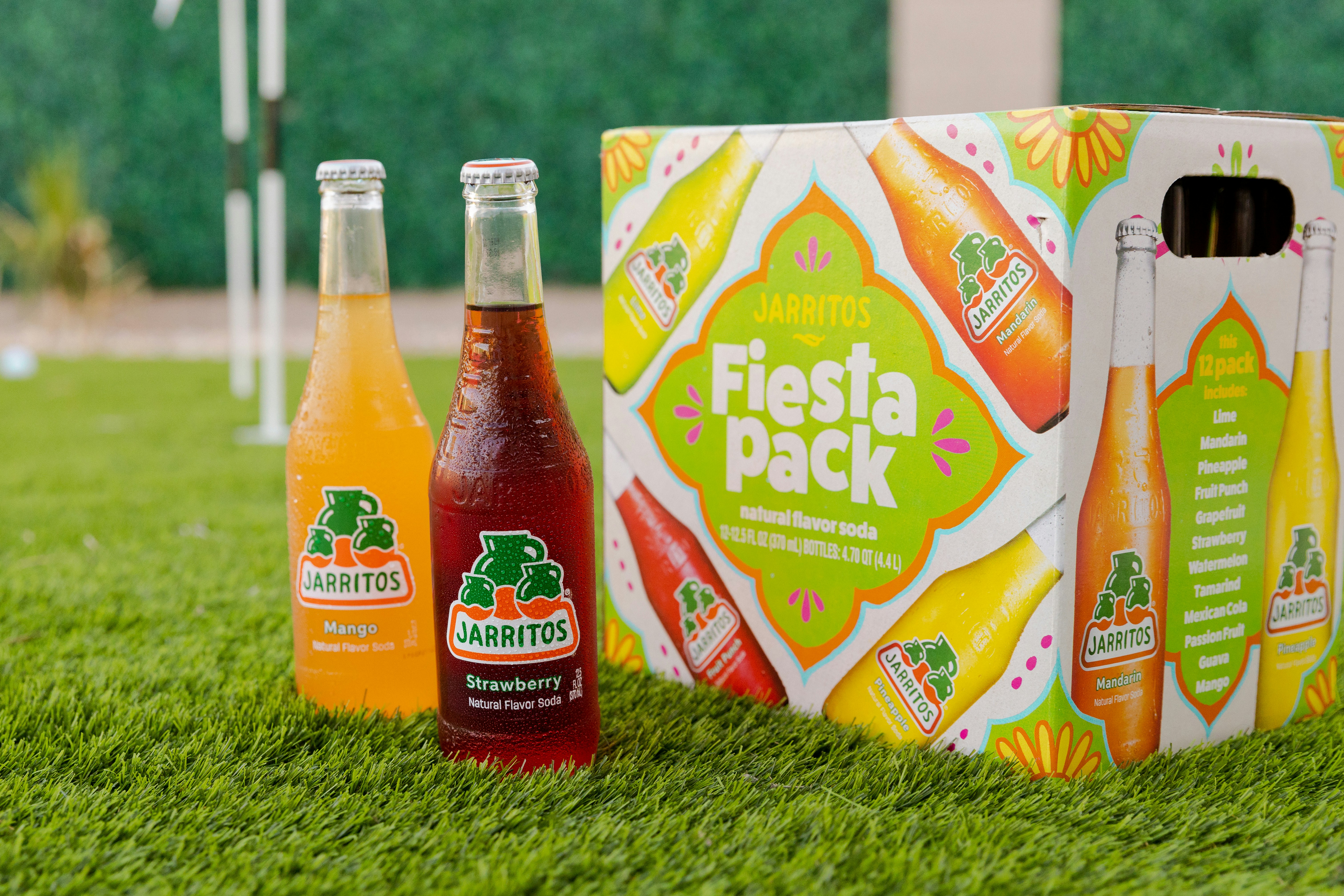 three bottles of soda sitting on top of a lush green field