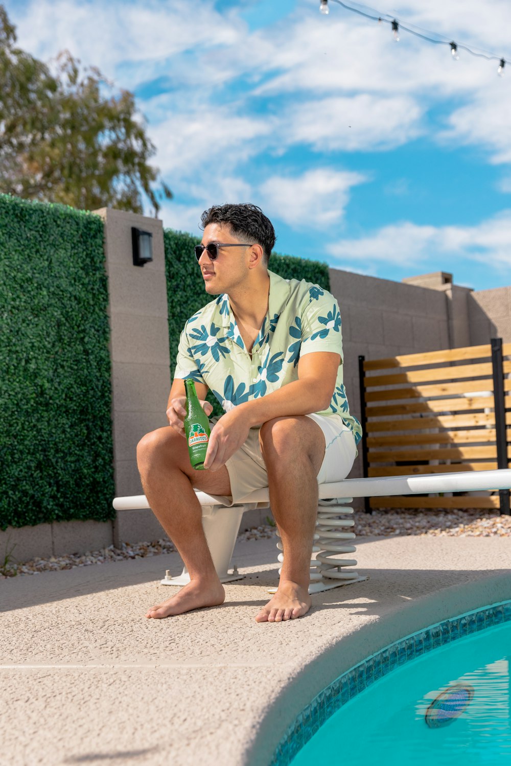 a man sitting on a bench next to a pool