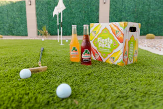 a couple of bottles of juice and a bat on some grass