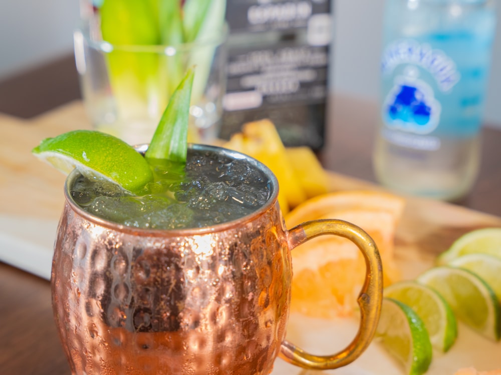 a copper mug filled with a drink and garnished with a green leaf