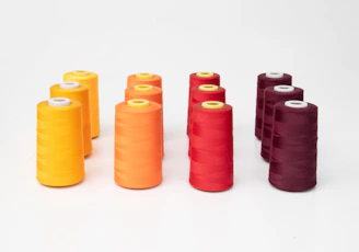 Yellow mustard-themed filament spools arranged neatly with faint comic strip shadows behind.