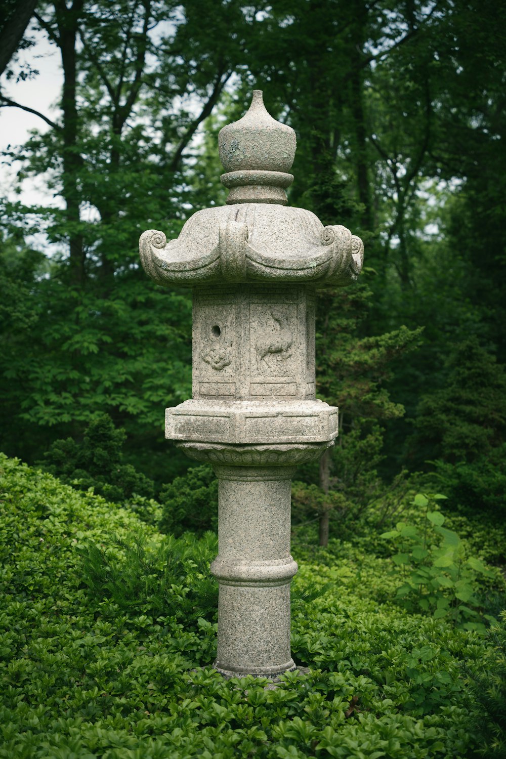 a stone statue in the middle of a garden