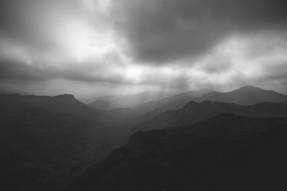 a black and white photo of mountains under a cloudy sky