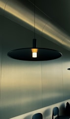 A sleek, modern pendant light casting a warm glow over a minimalist room.