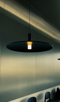 A sleek, modern pendant light casting a warm glow over a minimalist living room.