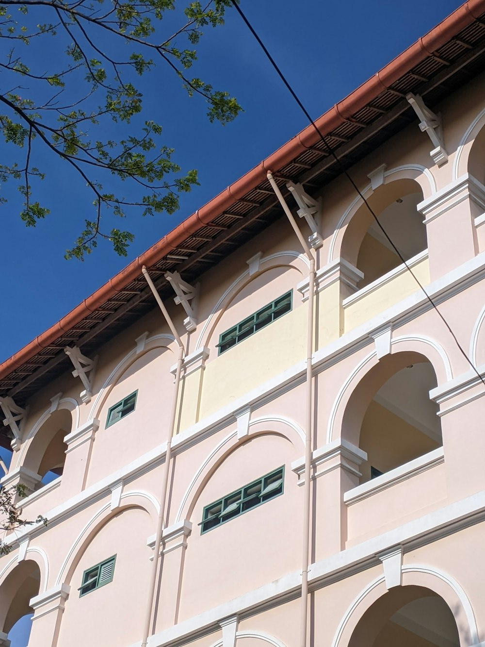 a pink building with arched windows and a red roof