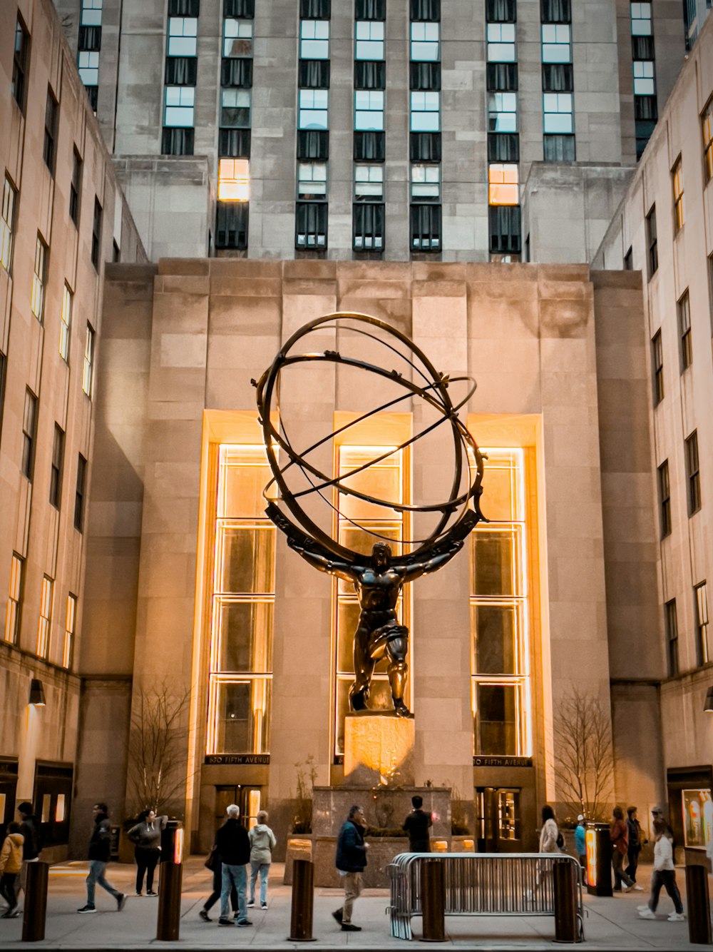 una statua di una persona che tiene un globo di fronte a un edificio