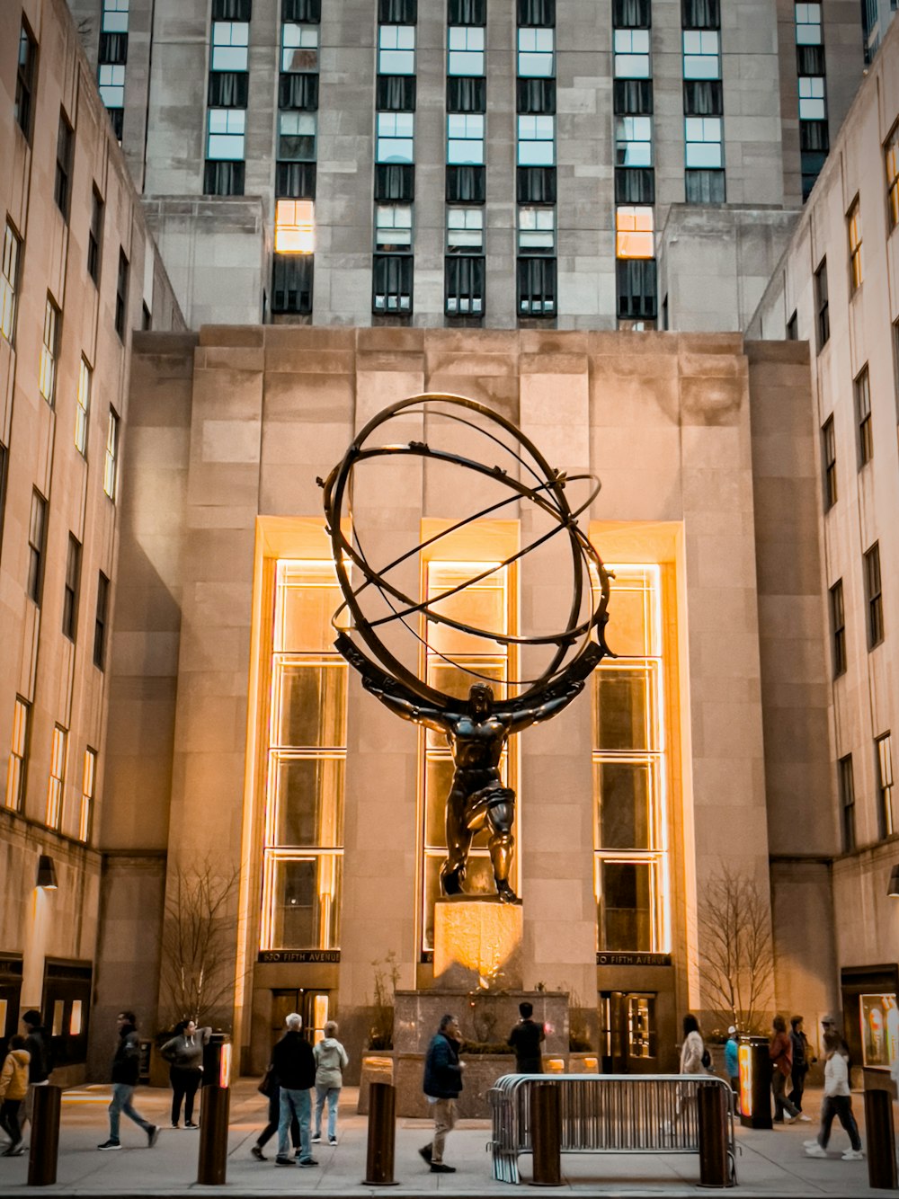 una estatua de una persona sosteniendo un globo terráqueo frente a un edificio