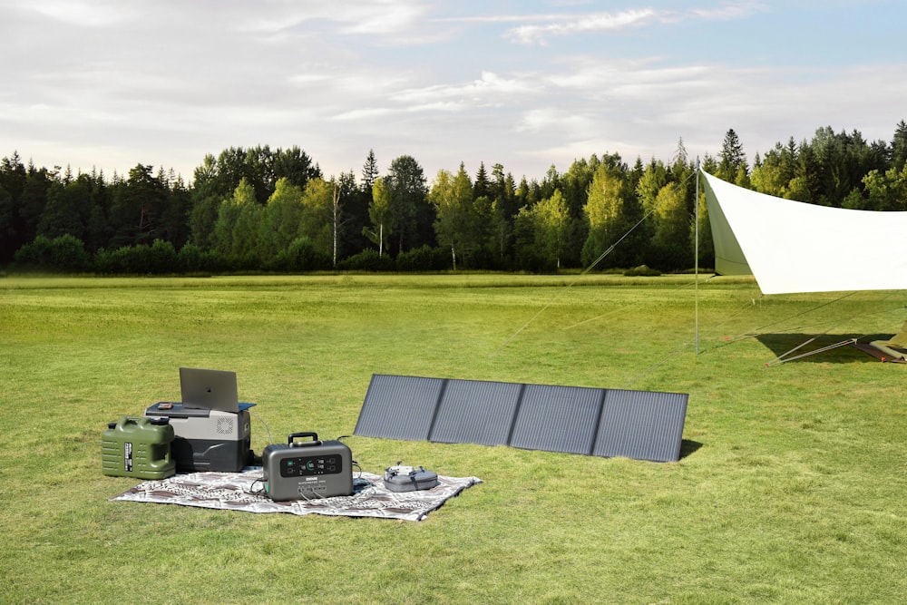 a field with a tent, laptops and other electronics on it