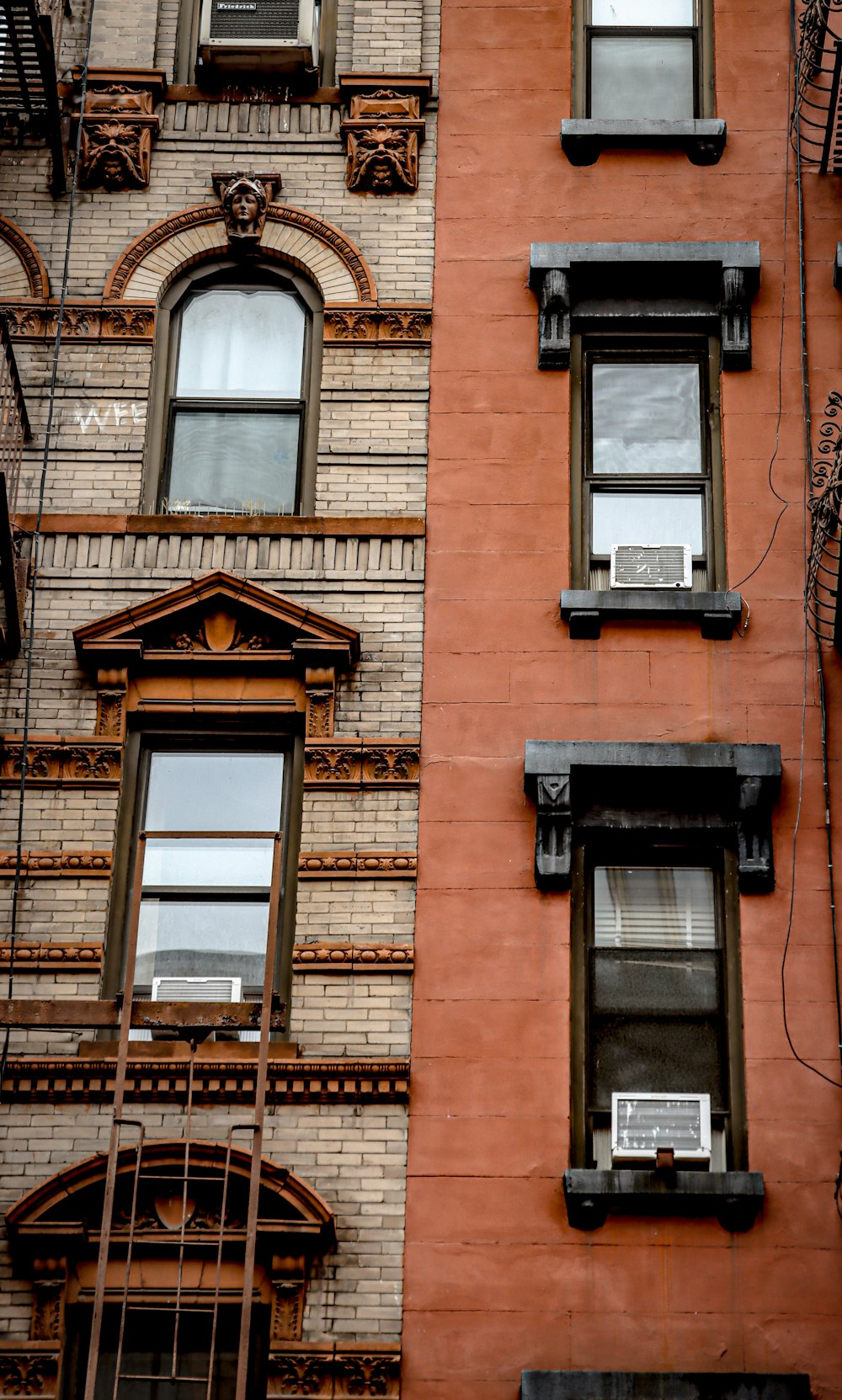 a red brick building with two windows and a fire escape