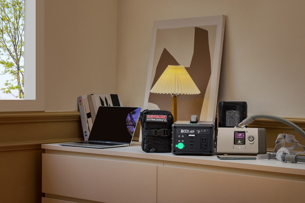 a table with a lamp, a camera, a laptop and other items on it