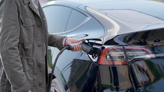 Technician connecting a charging cable to an electric car at a public charging point.