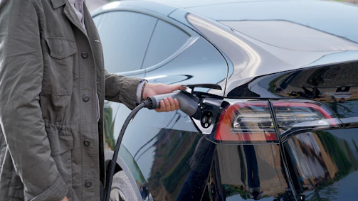 Technician connecting a charging cable to an electric car at a public charging point.