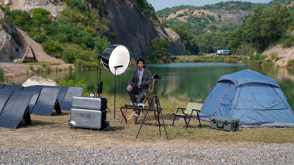 a man standing next to a tent near a lake