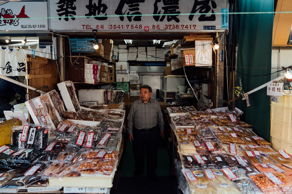 a man standing in front of a store filled with lots of food