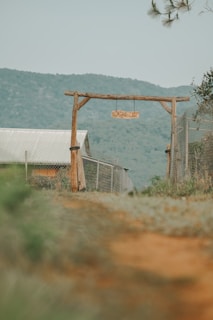 A welcoming rustic farm gate with greenery and a small wooden sign that reads 'one leaf farm'.
