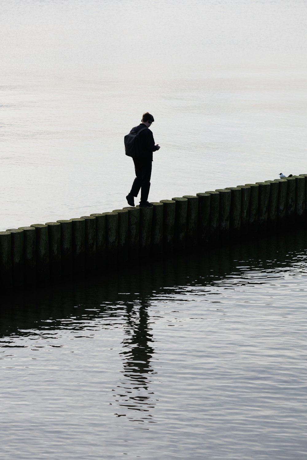 a man walking along a pier next to a body of water