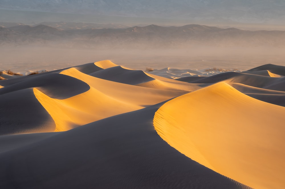 a group of sand dunes with mountains in the background