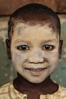 A child wearing a handmade mask, beaming with pride during a creative workshop.