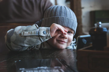 a young boy sitting at a table with his hands on his face