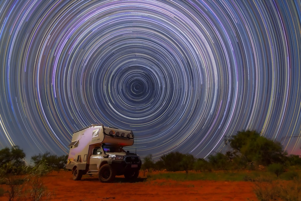 a truck parked in the middle of a field under a star filled sky