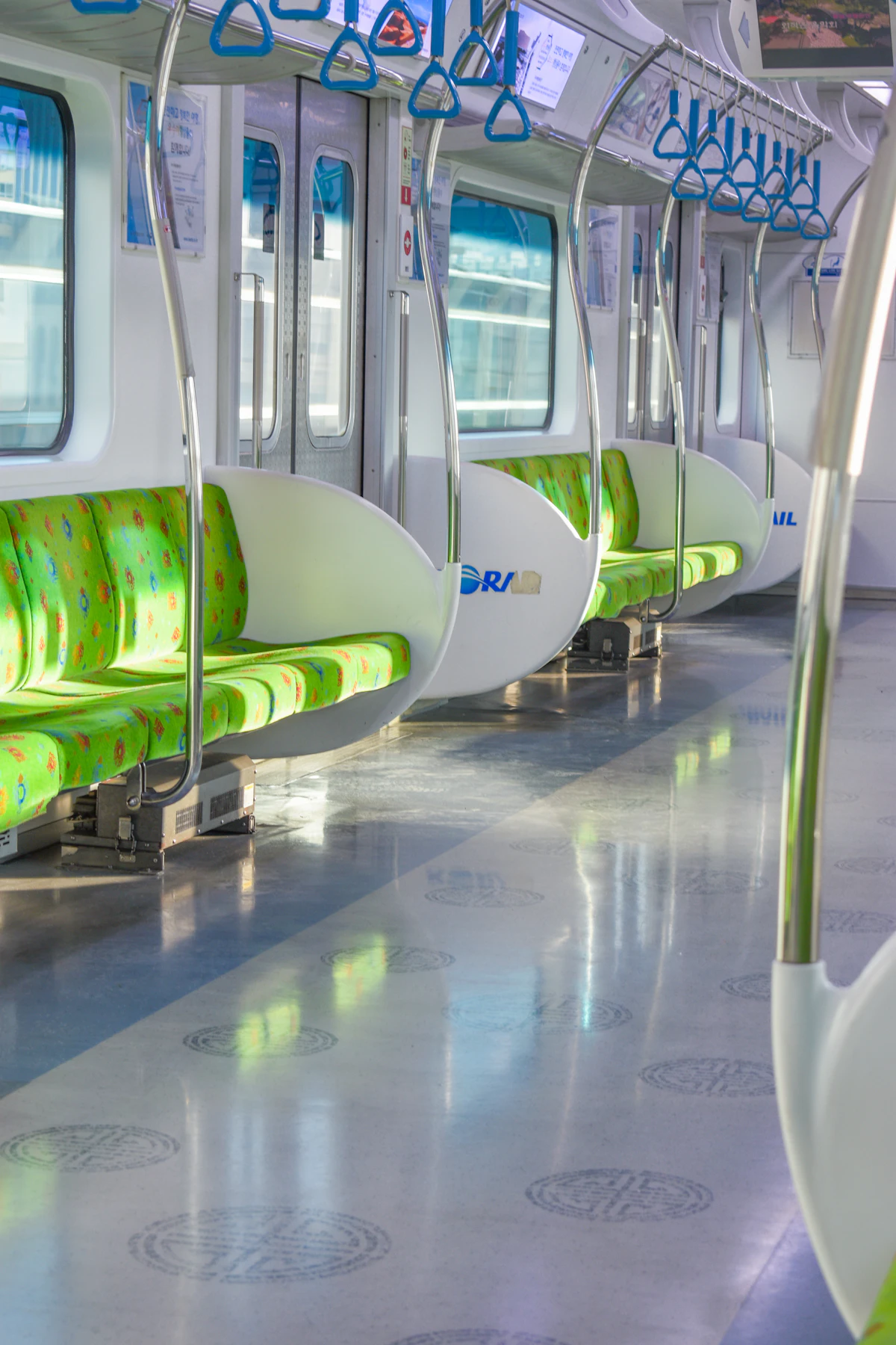 Empty Seoul subway car with green seats and blue hand straps