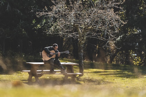 a man sitting on a bench playing a guitar