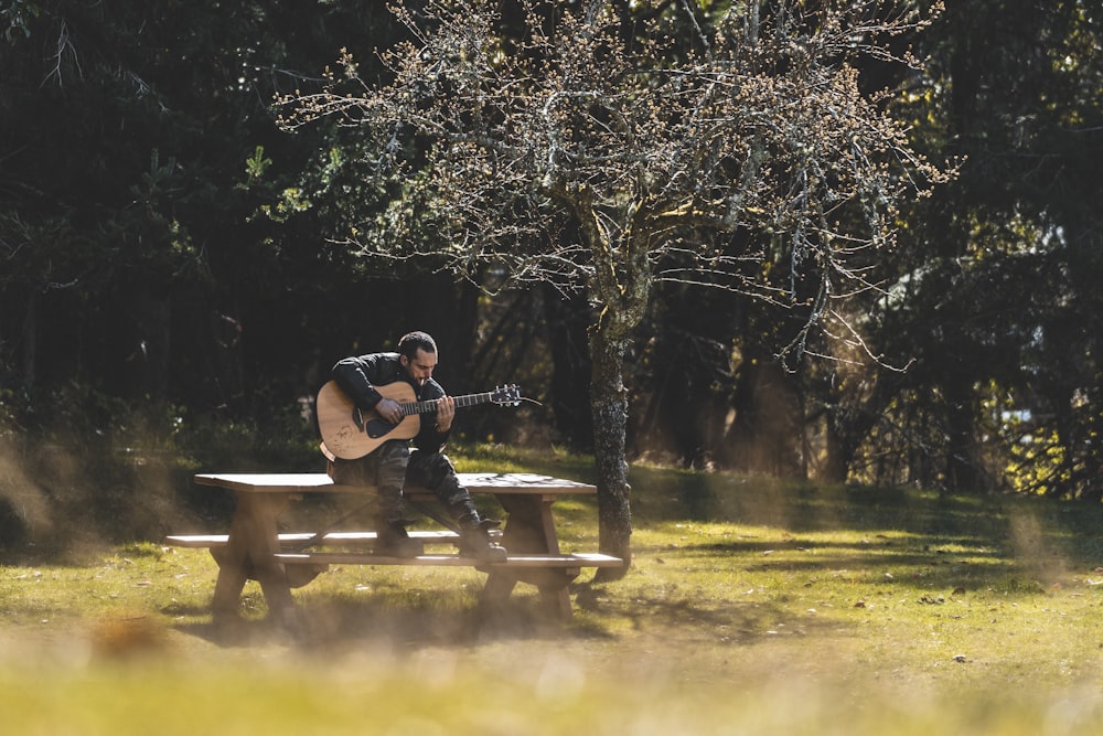 Un hombre sentado en un banco tocando una guitarra