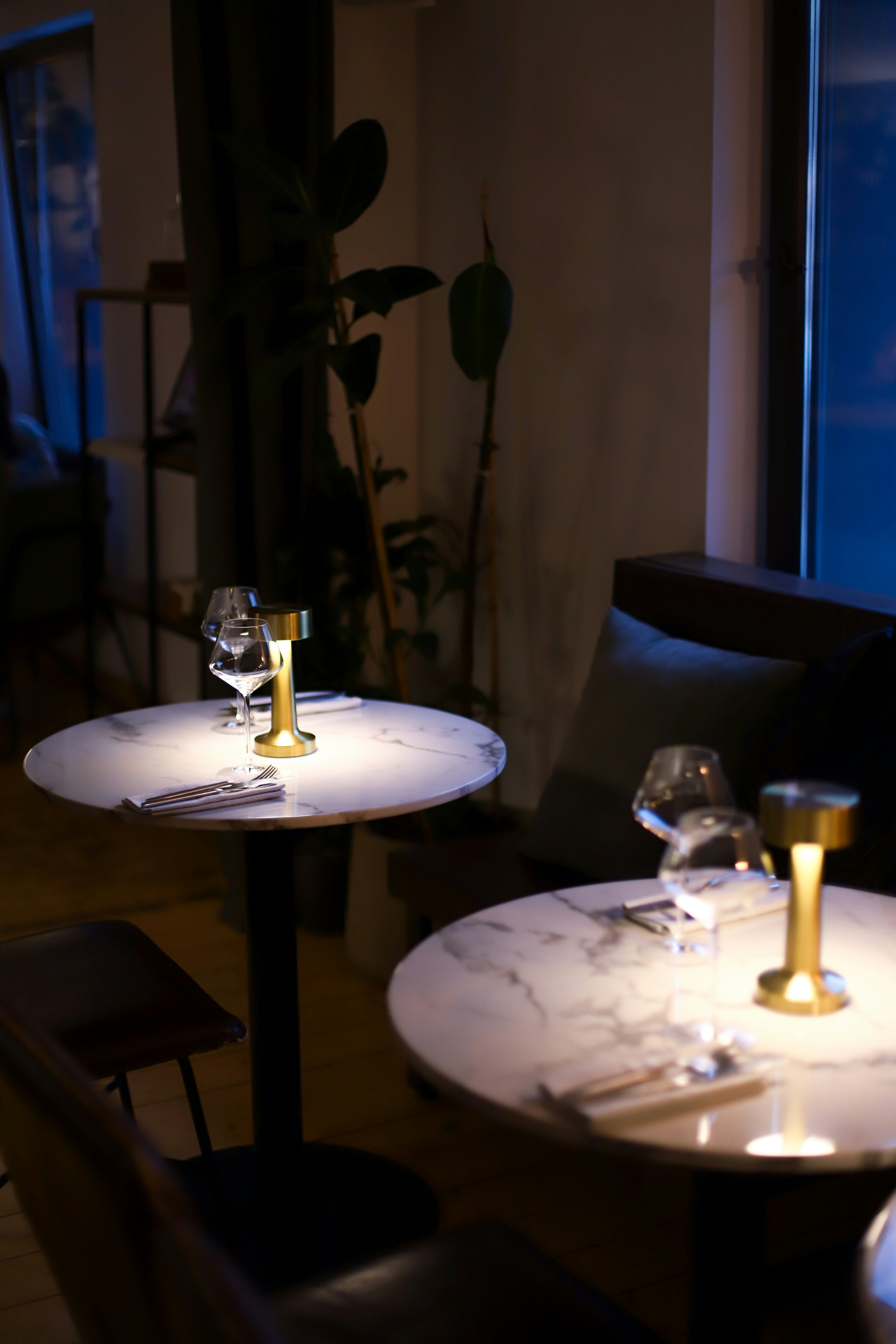 Dos mesas de mármol puestas para cenar en el interior de un restaurante.