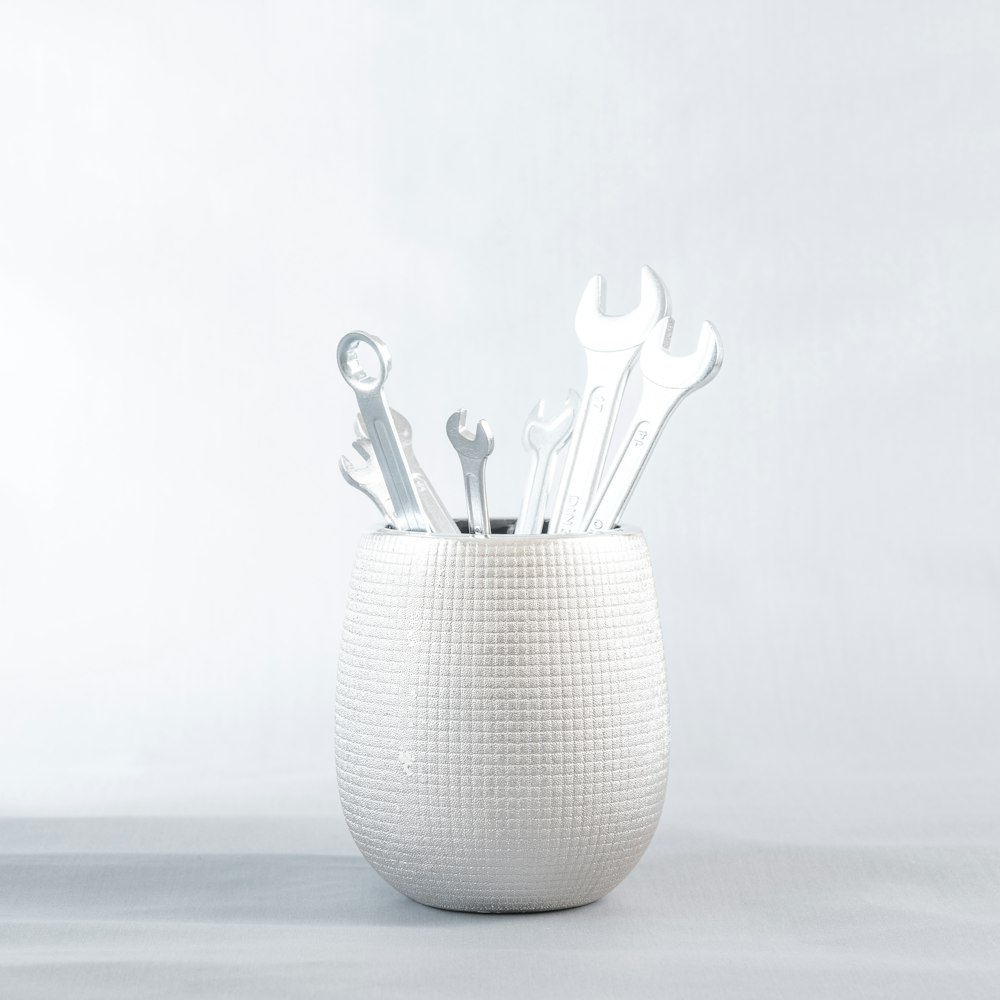 a white vase filled with lots of wrenches