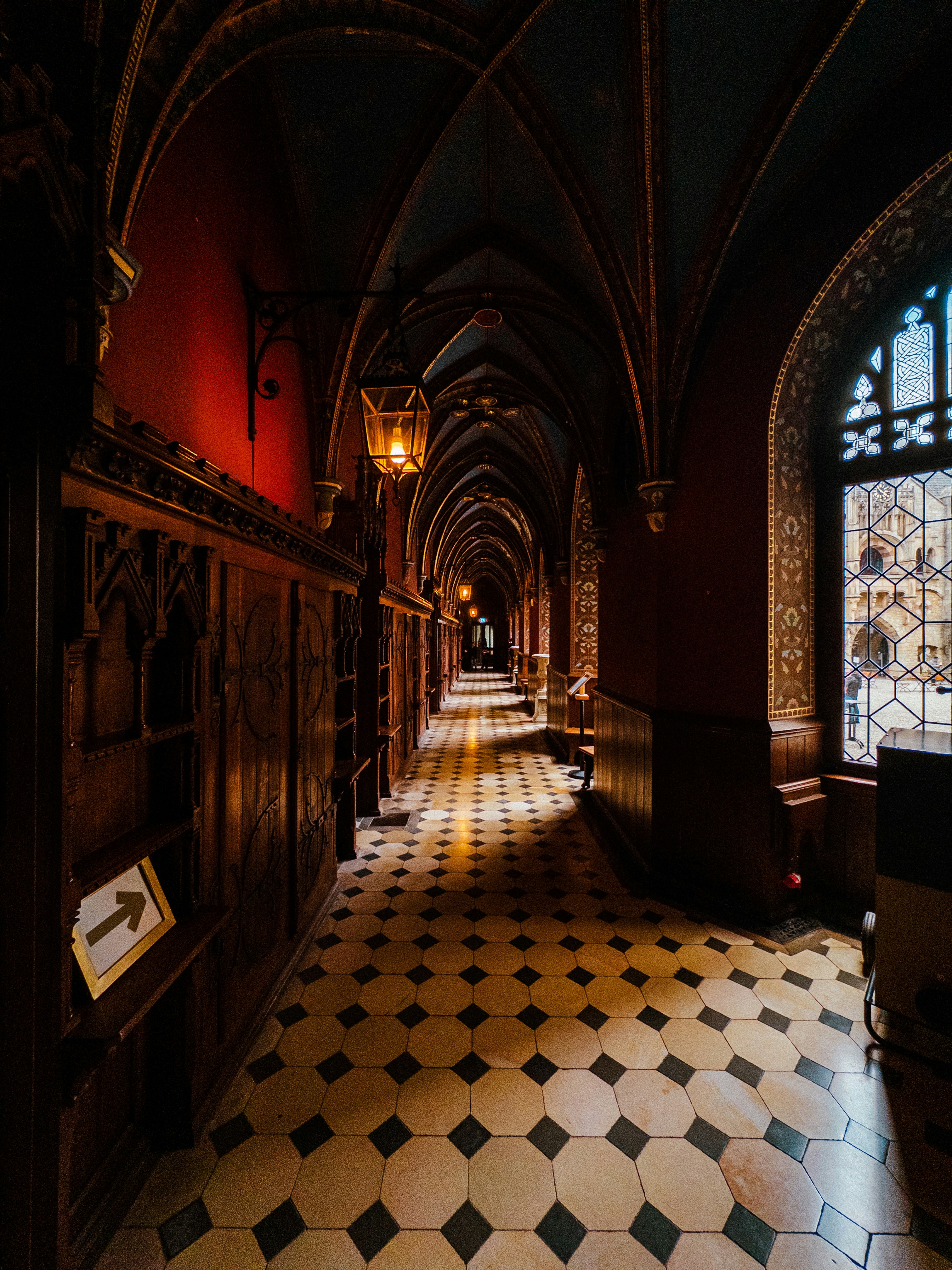 a long hallway with a checkered floor and arched windows