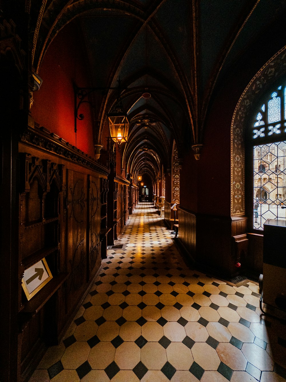 a long hallway with a checkered floor and arched windows