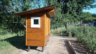 A sturdy waterproof storage box placed on a wooden deck with garden tools beside it under bright sunlight.