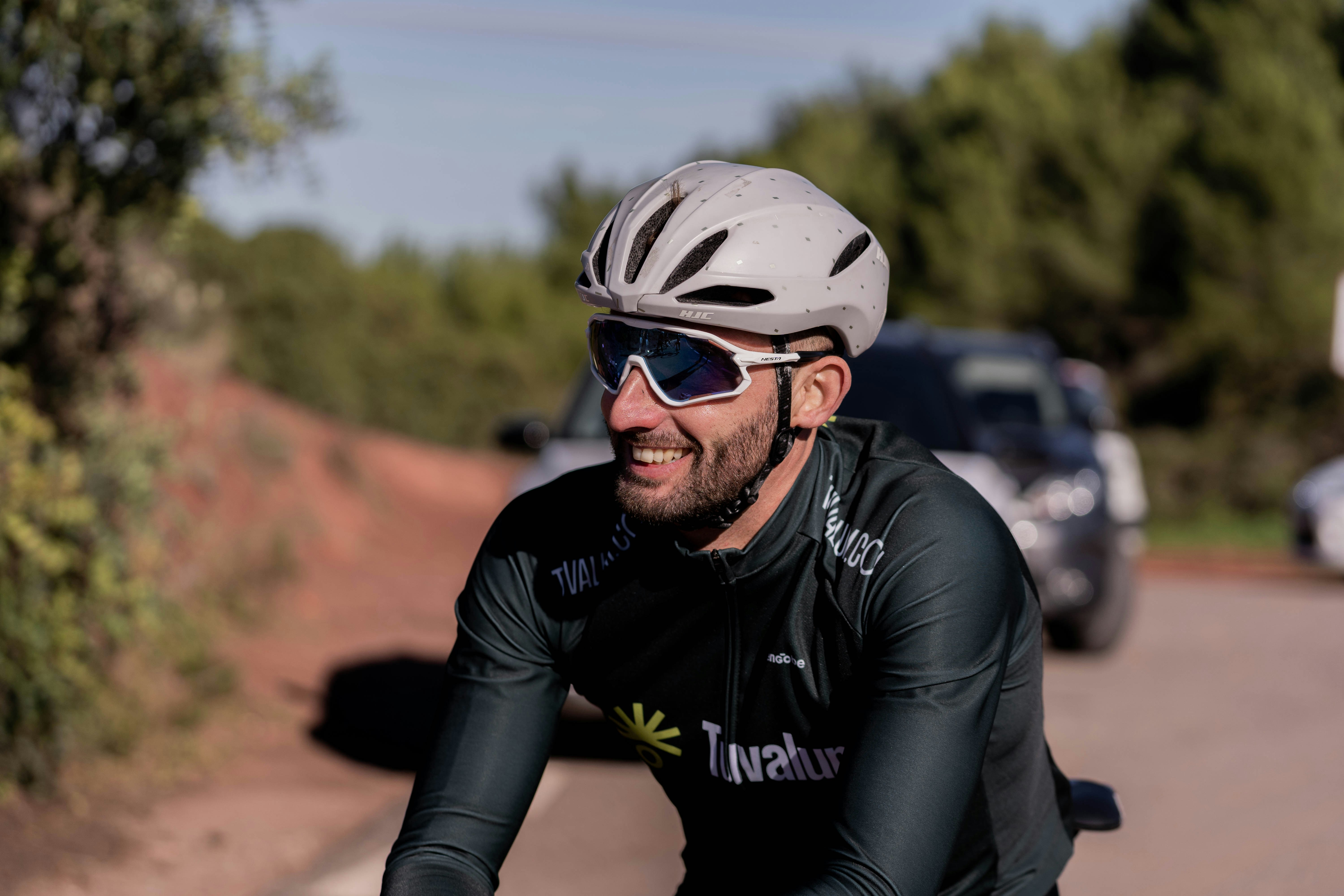 a man riding a bike down a street next to a forest