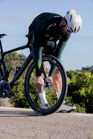 Bakti adjusting his bike gears before a morning training ride on a quiet road.